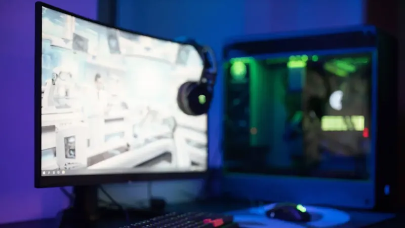 High-tech gaming setup featuring a curved monitor, RGB keyboard, and vibrant lighting.