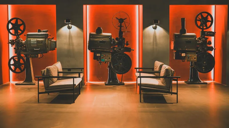 A cozy retro cinema room showcasing vintage film projectors and comfortable seating.