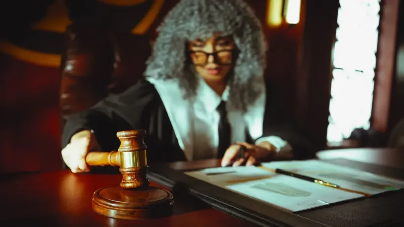 Juez femenina en un tribunal, centrándose en documentos legales con un mazo.