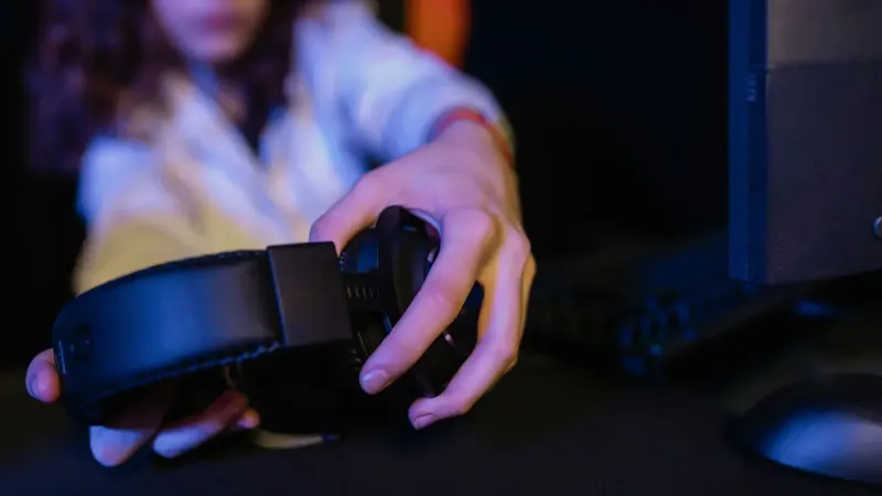Primer plano de una persona que sostiene un auricular de juego en una configuración de computadora.