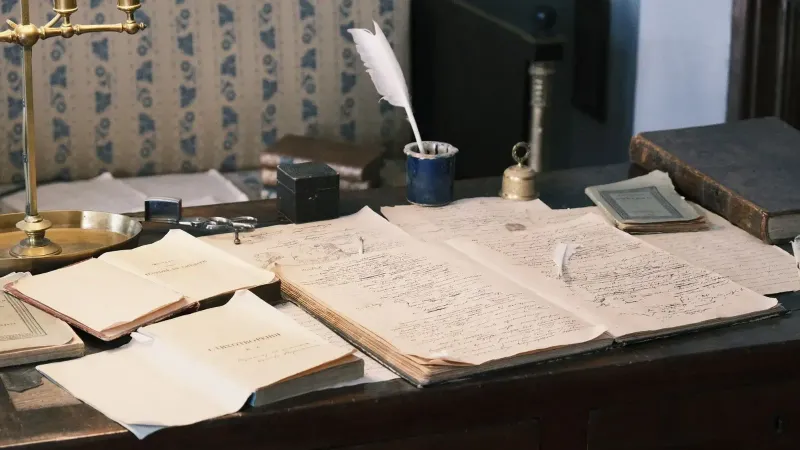 Acogedor estudio con escritorio vintage, libros abiertos y pluma para una sensación literaria clásica.
