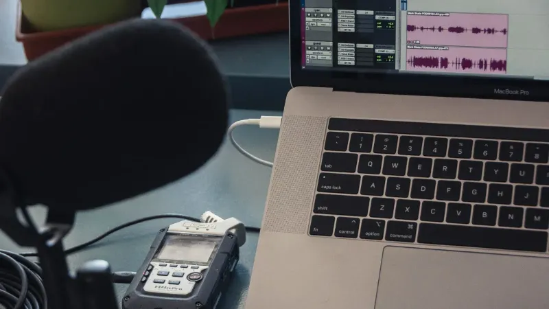 Microphone and laptop setup for audio recording in a studio environment.