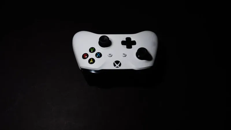 A close-up of a white Xbox controller on a black background, highlighting its modern design.