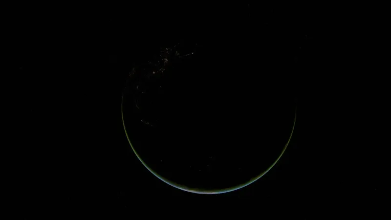 Stunning crescent view of Earth at night, highlighting city lights and vast oceans.