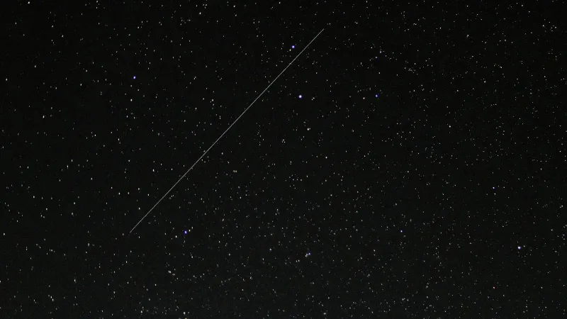 Captivating starry night sky with a visible shooting star streaking across the cosmic backdrop.