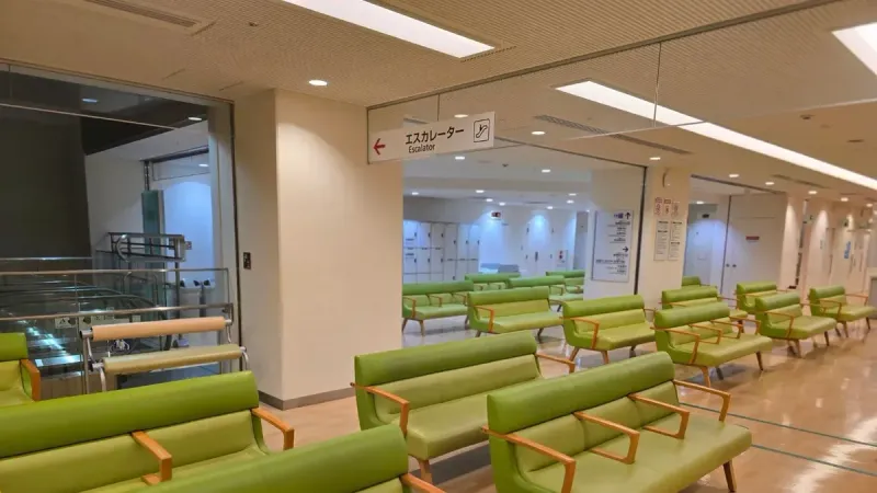 Empty hospital waiting area with green seats in Shibuya, Tokyo.