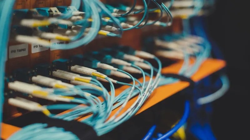 Closeup of many cables with blue wires plugged in modern switch with similar adapters on blurred background in modern studio