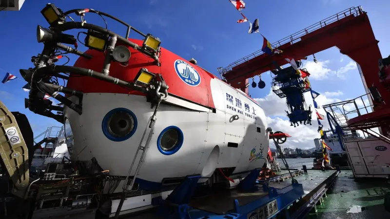 A close-up view of a submarine on a dock, under a clear blue sky.