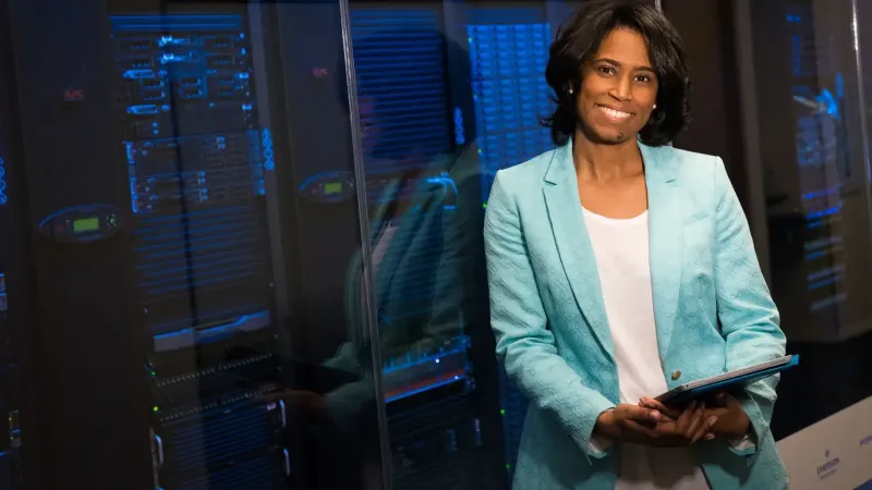 Mujer sonriente en centro de datos que muestra experiencia en tecnología.