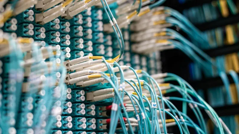 From below of long thin blue cables connected to row of small white connectors on system block in data center