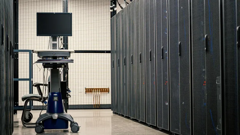 Contemporary computer on support between telecommunication racks and cabinets in modern data center