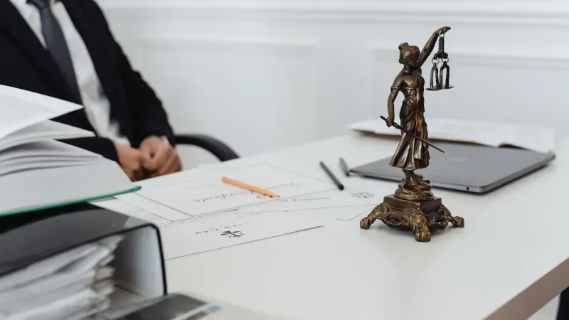 A legal professional's workspace featuring Lady Justice statue, documents, and a laptop.