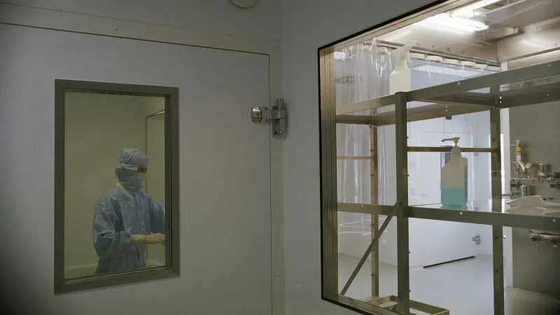 Image of a cleanroom in a medical facility featuring sterile equipment and a person in protective clothing.