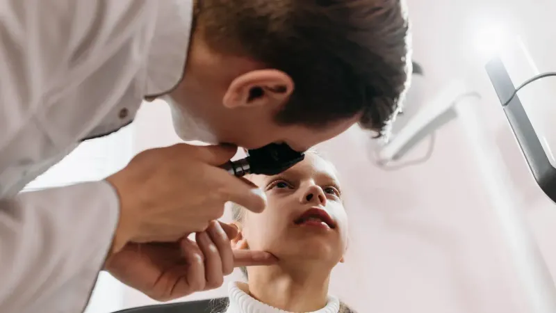 El médico realiza un examen ocular en una niña en un entorno clínico, mostrando la atención médica pediátrica.