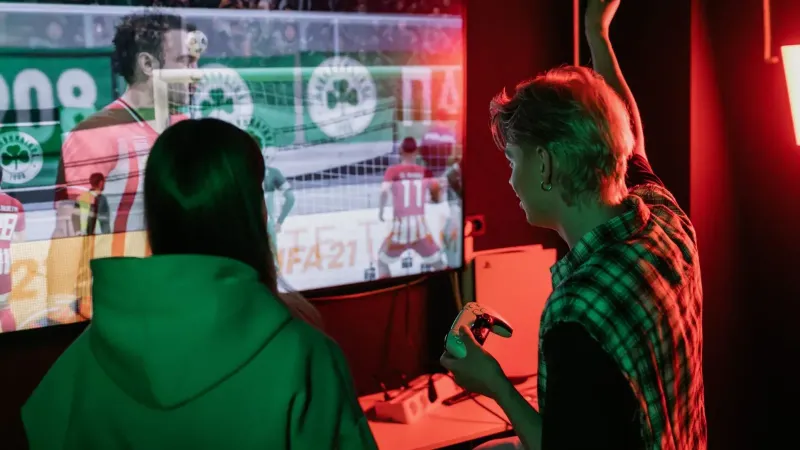 Two friends enjoying an exhilarating video game session indoors, captured with vibrant lighting.