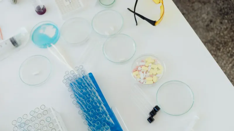Aerial view of laboratory equipment including petri dishes, pills, test tubes, and syringes.
