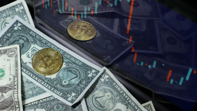 Bitcoin coin on US dollar bills with a stock market chart background. Represents cryptocurrency and finance.