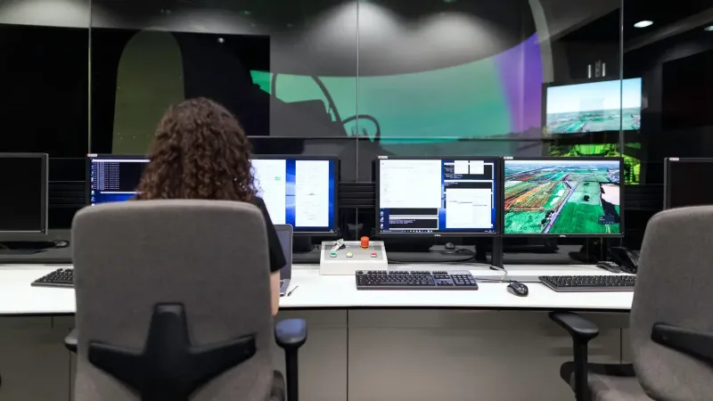 Female engineer managing multiple screens during a technology simulation in a control room.
