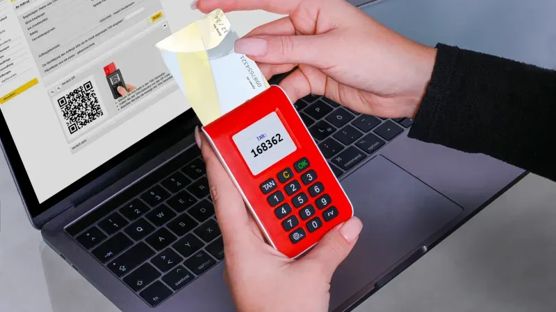 Woman using TAN generator for secure online payment on laptop, enhancing cybersecurity.