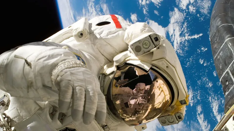 Astronaut floating in space during a spacewalk, visible Earth in the background.