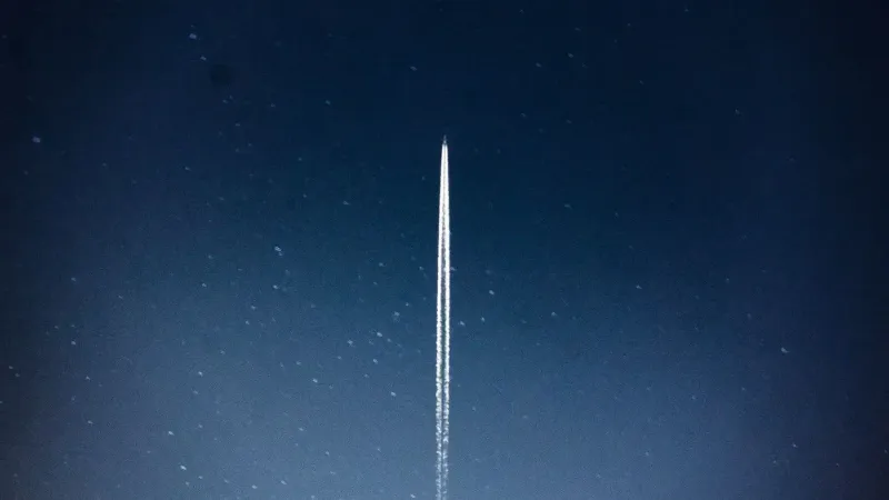 A rocket streaks through a starry night, leaving a trail in outer space.