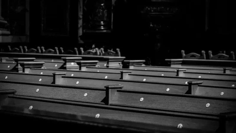 Una serena imagen en blanco y negro de los bancos de la iglesia con luz suave, evocando una atmósfera pacífica y contemplativa.