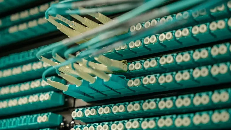 Detailed view of fiber optic cables connected to a server rack, showcasing modern technology.
