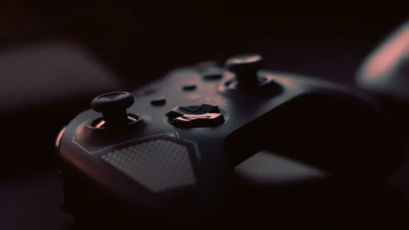 Un primer plano de un controlador de juego con poca luz, destacando su diseño y botones.