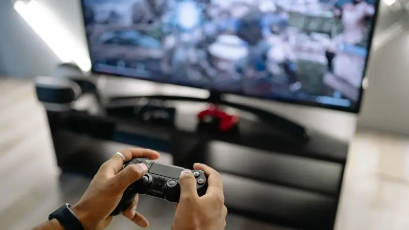 Close-up de manos sosteniendo un controlador de juegos mientras juega videojuegos en interiores.