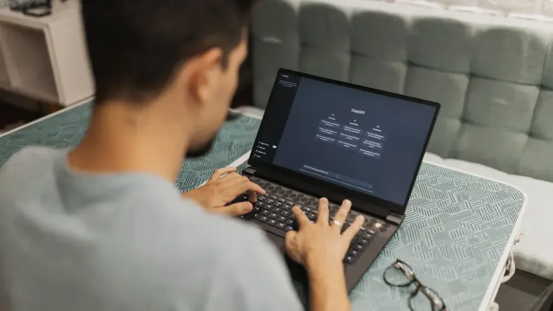 A man working on a laptop displaying ChatGPT's interface in an indoor setting.