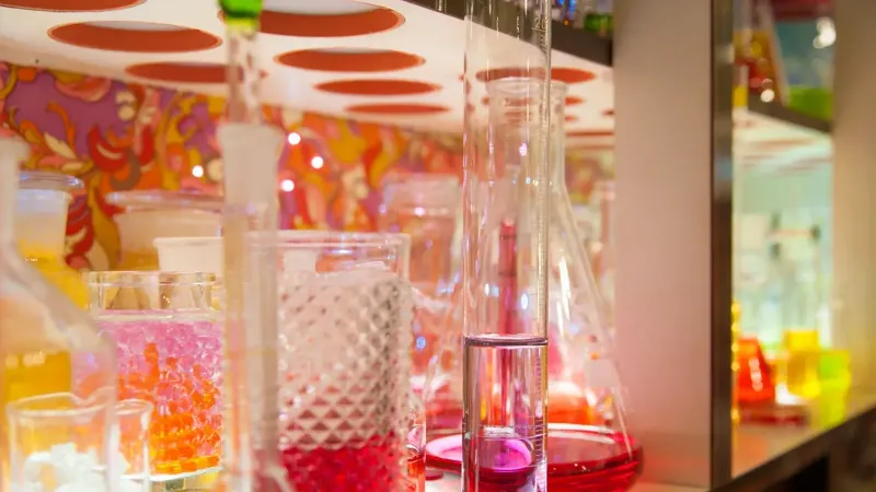 A collection of colorful glassware with vibrant liquids on display in a lab setting.