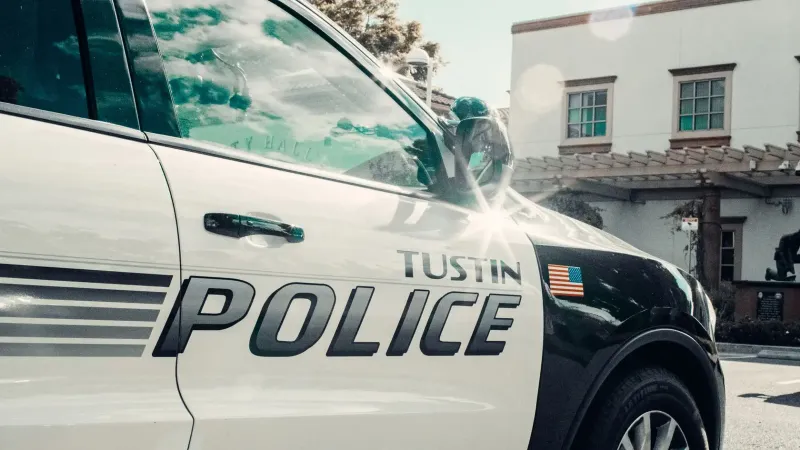 Close-up de un coche de la policía de Tustin estacionado cerca de un edificio del ayuntamiento a la luz del día.