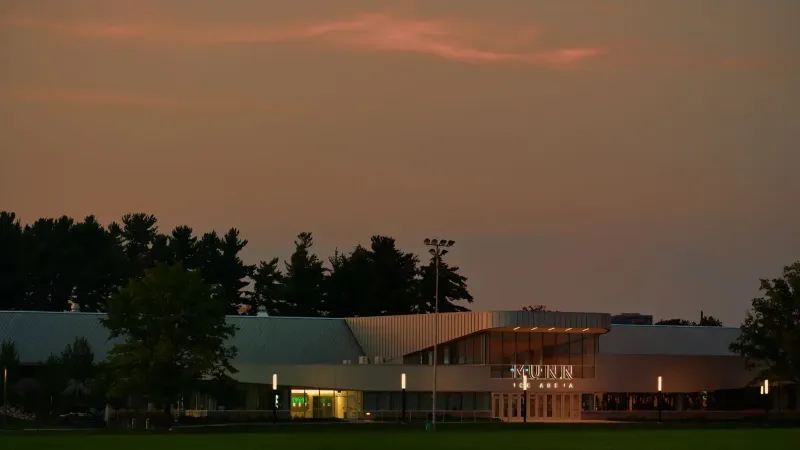 The Kunn Ice Arena illuminated in the early evening, set against a moody sky in East Lansing, Michigan.