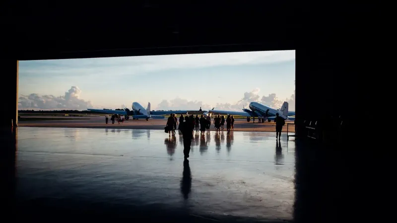Siluetas de viajeros irreconocibles caminando hacia grandes aviones ubicados en la pista de aterrizaje del aeropuerto