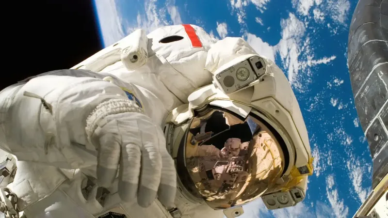 Astronaut floating in space during a spacewalk, visible Earth in the background.