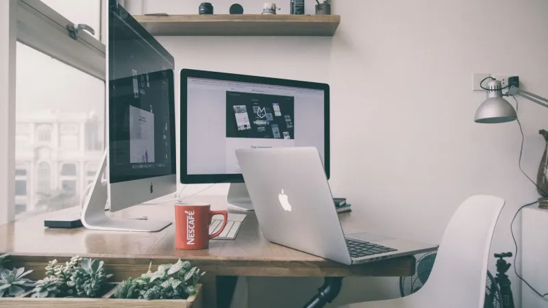 Sleek home office setup with dual monitors, a laptop, and minimalist decor.