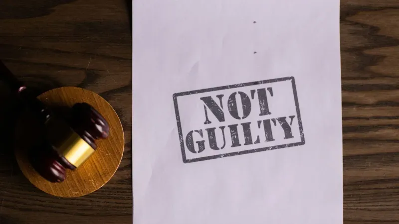 A courtroom document labeled 'Not Guilty' beside a gavel symbolizes justice.