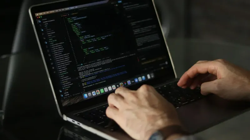 Primer plano de manos codificando en una computadora portátil, centrándose en la productividad de programación.