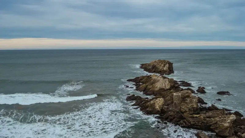 Captura de rocas y olas escarpadas en la playa de Zarautz en un día nublado.