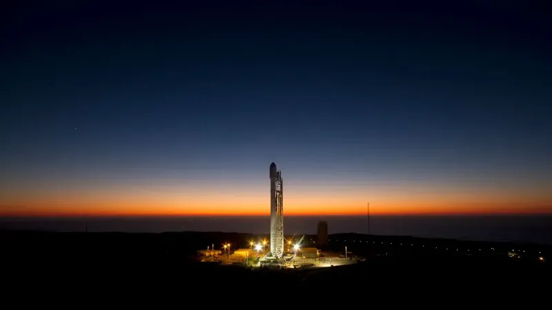 A powerful rocket stands ready on its launch pad against a stunning twilight sky.