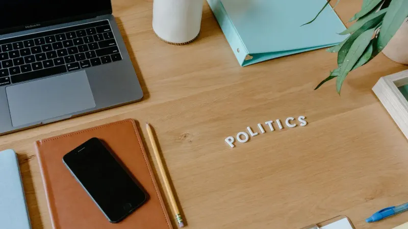 Neat office desk setup with laptop, smartphone, and political theme.
