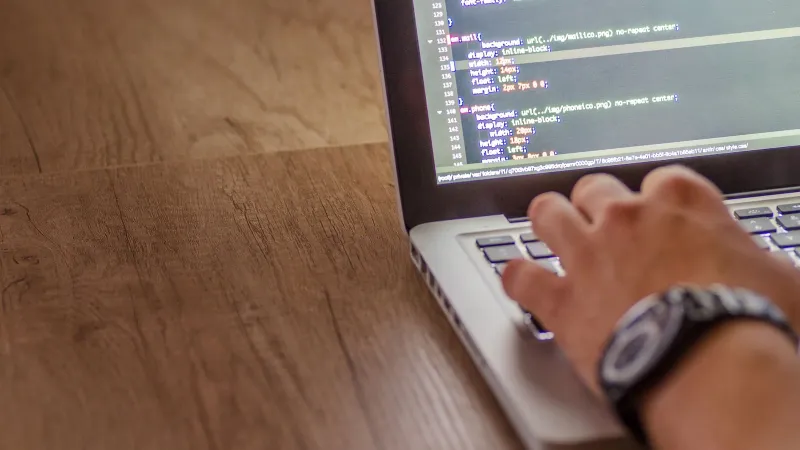 Close-up of a person coding on a laptop, showcasing web development and programming concepts.