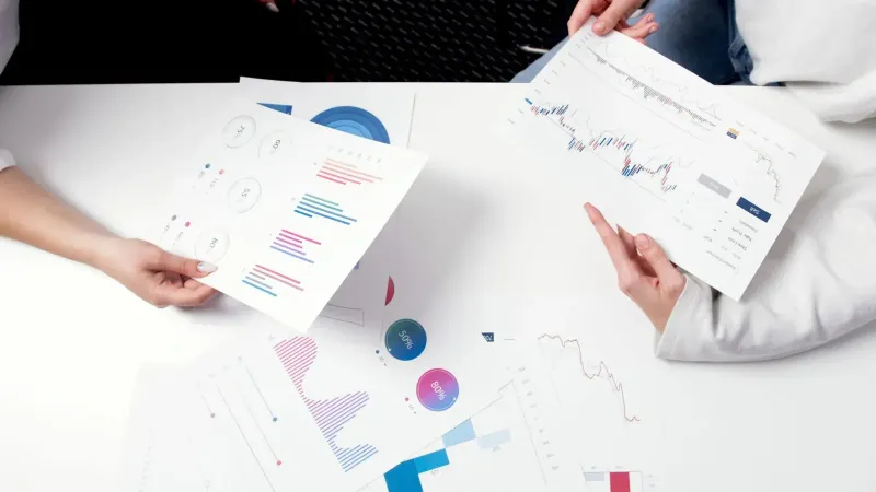 Hands holding business charts and graphs during a meeting, showcasing financial analysis and investment strategy.