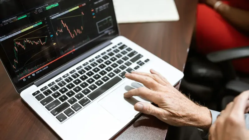Close-up de la mano usando laptop para el análisis del mercado de valores en el entorno de la oficina.