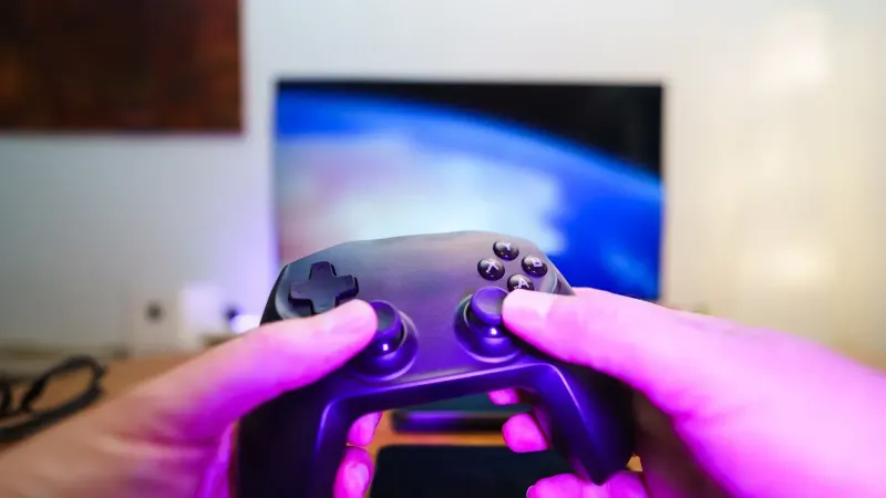 Close-up of hands holding a game controller in front of a TV screen. Perfect for entertainment setups.
