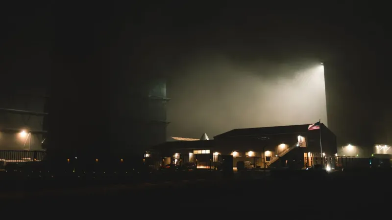 Una espectacular vista nocturna de una instalación industrial en un centro de exploración espacial con iluminación atmosférica.