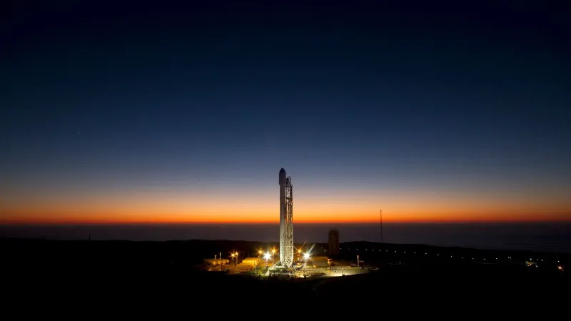 A powerful rocket stands ready on its launch pad against a stunning twilight sky.