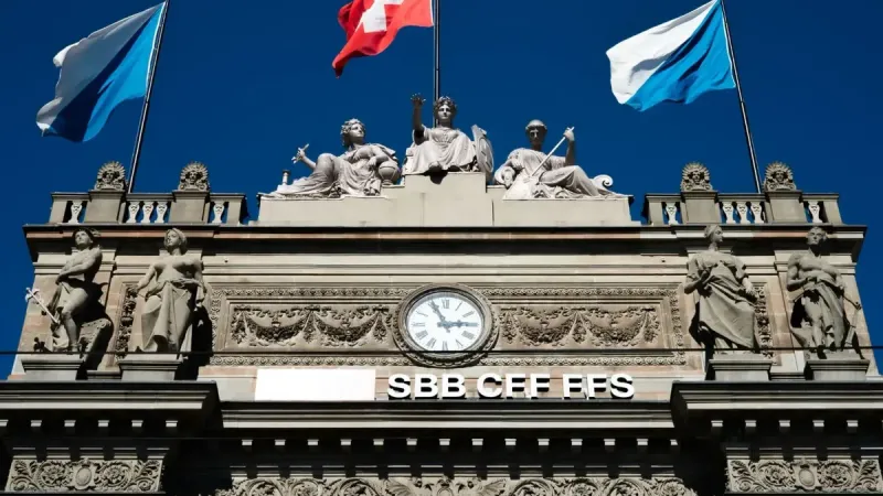 Edificio histórico SBB con banderas suizas y esculturas en Zúrich.