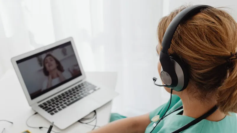 Medical professional consulting a patient online via laptop for telehealth services.