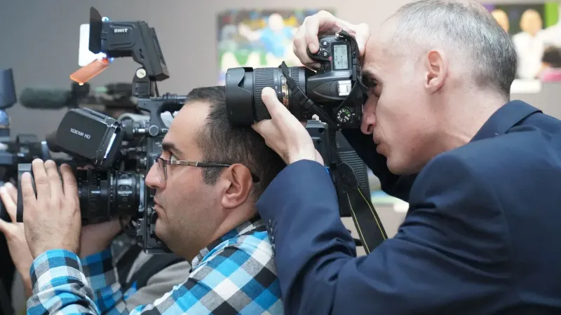 Photographers focusing on event coverage with advanced cameras indoors, showcasing media professionals in action.